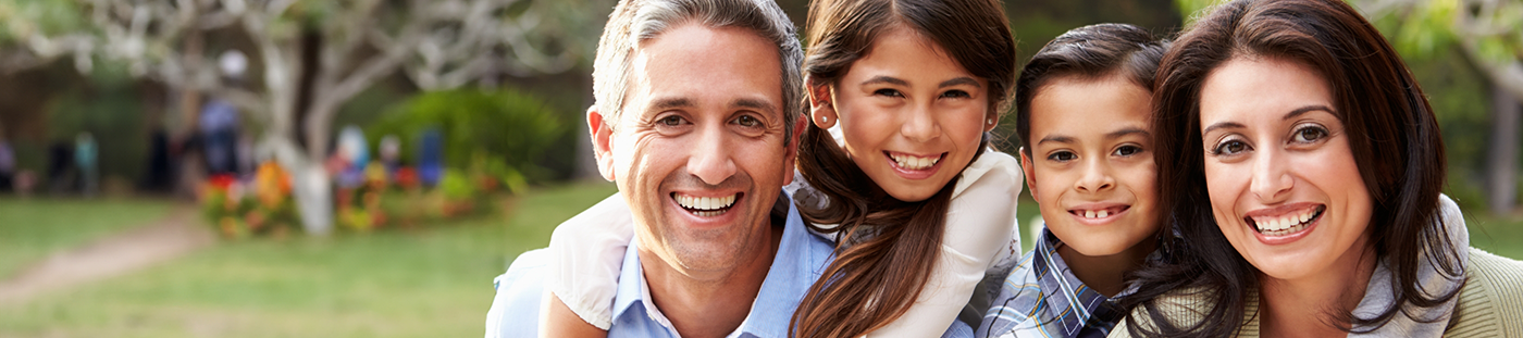 Family of four grinning outdoors